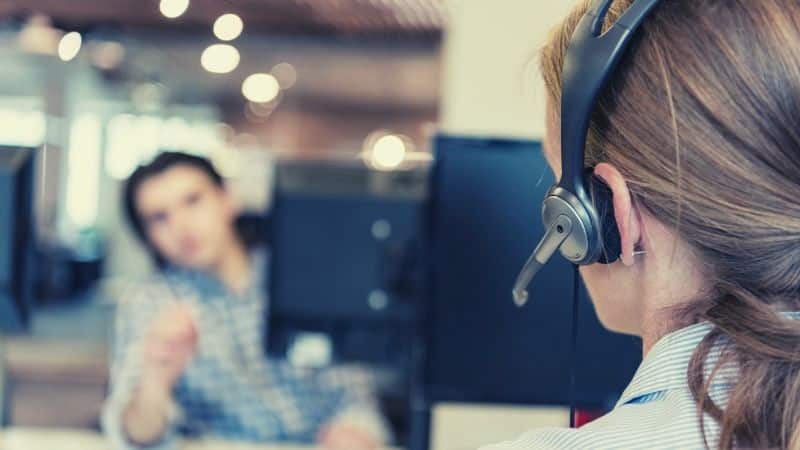 sales technology - woman on the phone with headset in front of computer